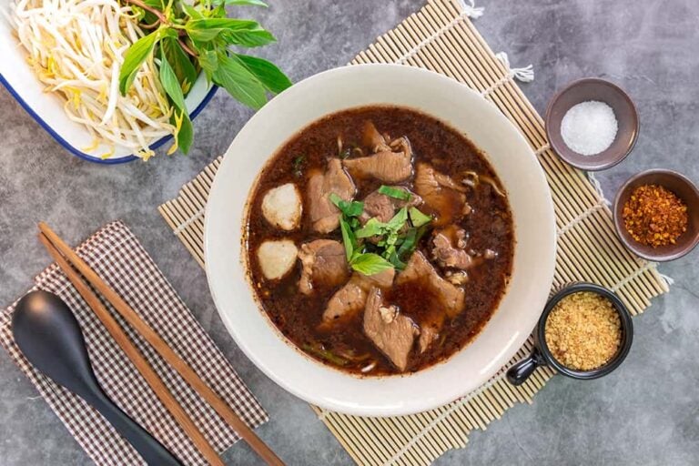 濃厚な肉のスープに豚肉や肉団子がたっぷりと入ったタイの定番の食べ物「ボートヌードル」。もやしやハーブ、調味料などの薬味とともにテーブルに並べられた様子