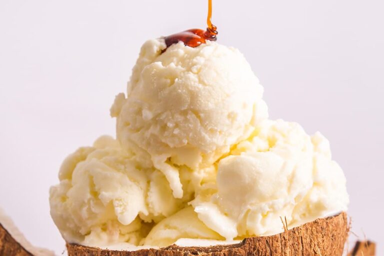 ココナッツの殻を器にしてたっぷりと盛り付けられた、タイの冷たい食べ物「ココナッツアイス」。暑い日にうれしい南国のデザートに甘いシロップがとろりと、かけられている様子