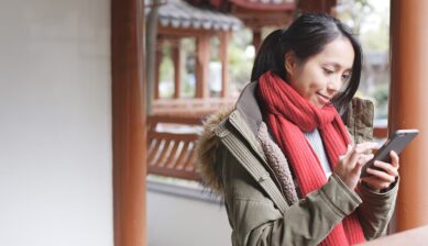 旅行先の屋外でスマートフォンを操作する女性