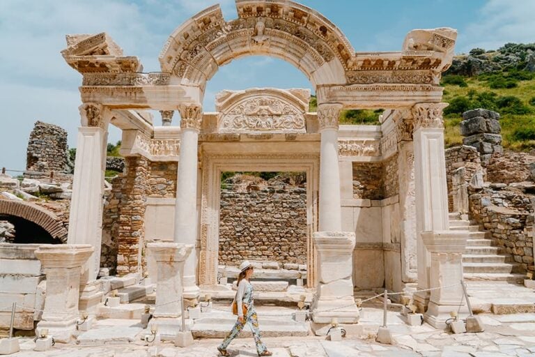 精巧な彫刻が施された大理石の遺跡の前を観光客が歩く、古代の歴史を色濃く残すトルコ・エフェソス古代都市の風景