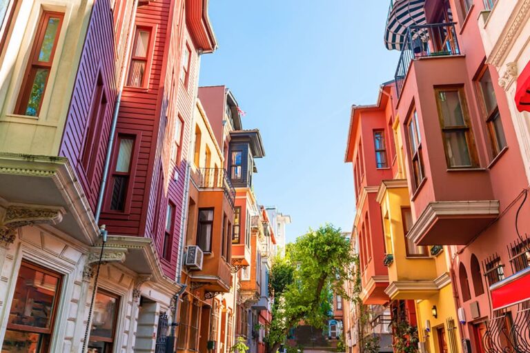 青空の下、トルコの都市に昔ながらの街並みが残るクズグンジュック地区の、カラフルな木造建築が連なる路地の風景