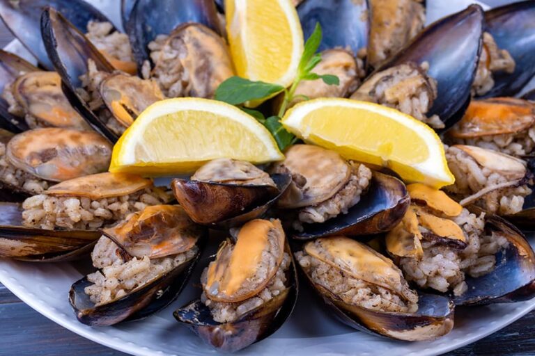 ムール貝の殻にスパイスの効いたピラフを詰め、くし切りのレモンを添えて提供される、トルコの定番屋台料理「ミディエ・ドルマ」