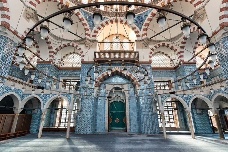 トルコの都市での街歩きで訪れたい、壁一面を覆う美しい青いタイルと大きなシャンデリアが印象的なモスクの内装