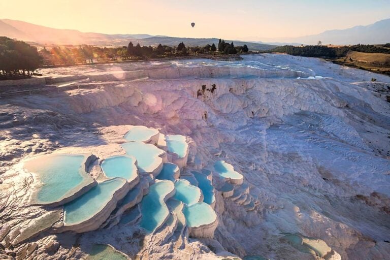 「綿の城」と称される真っ白な石灰棚に青い温泉水が階段状に連なる、柔らかな陽光に包まれたトルコ・パムッカレの幻想的な絶景