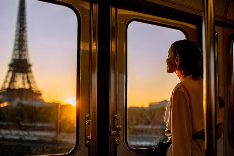 夕焼けに染まるエッフェル塔をメトロの車窓から眺めながら移動する女性観光客