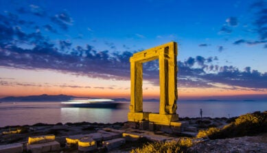 10月のギリシャ島巡り旅行で訪れたい、夕暮れの海に美しく浮かび上がるナクソス島の遺跡「ポルタラ」の幻想的な風景