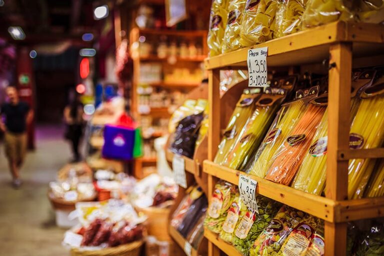 ローマのお土産探しに便利なスーパーマーケットの店内で、木製の棚にずらりと陳列された色鮮やかなパスタなどの食品