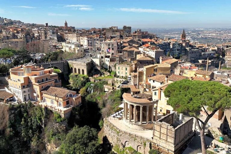 ローマ近郊ティボリの渓谷沿いに広がる歴史的な街並みと、崖の上に建つ円形の古代神殿遺跡の風景