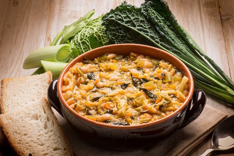 黒キャベツや豆などの野菜がたっぷり煮込まれた、イタリア・トスカーナ州の伝統的な具だくさんスープ「リボッリータ」と添えられたパン
