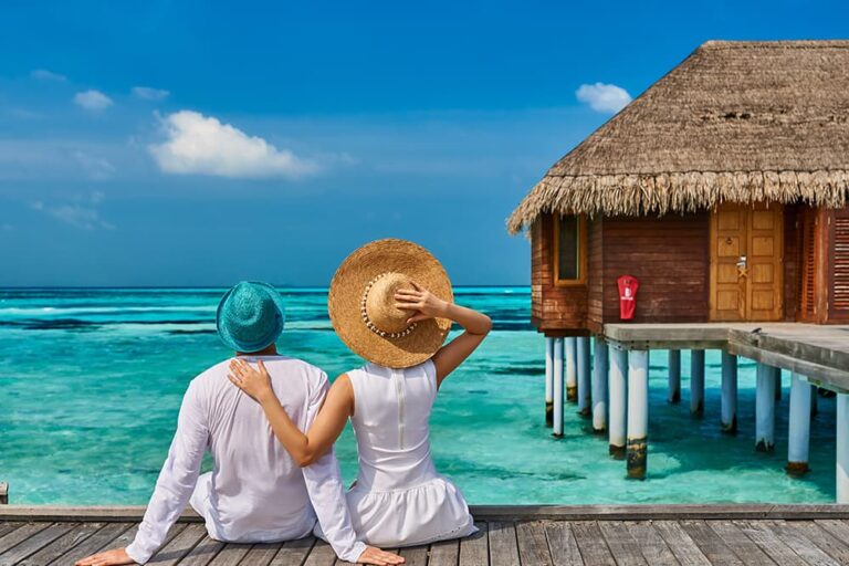モルディブの水上ヴィラで、美しい海を眺めながらリゾートでの2人の時間を満喫する新婚カップルの後ろ姿