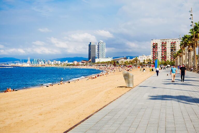 都市観光とビーチリゾートを同時に楽しめる、バルセロナの近代的なビル群と青い海が広がる活気あるビーチの風景