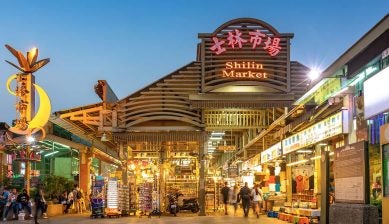 夕暮れ時にライトアップされた、台北を代表する夜市「士林市場（Shilin Market）」の入り口と行き交う人々の様子