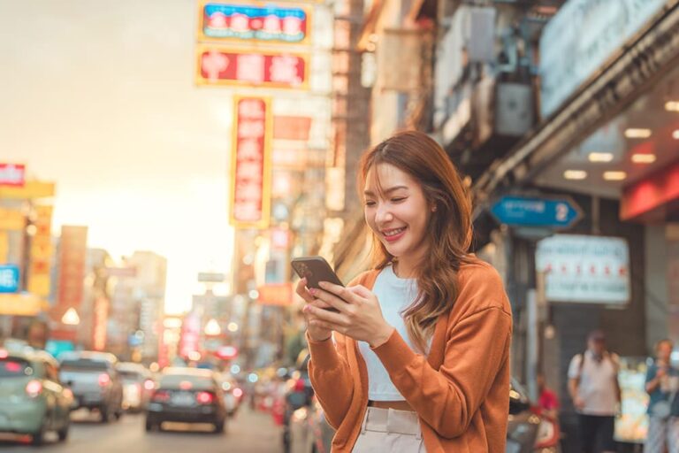 タイ・バンコクの街中でスマートフォンを操作し、旅行中にデータ通信を利用する女性の様子
