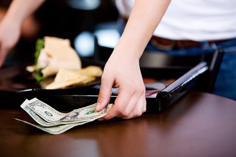 ハワイのレストランで、税金やチップを含めた食事代をテーブルに現金で支払う様