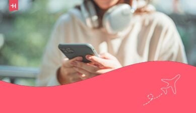 لقطة مقربة - يدا سائحة شابة ترتدي سماعات الرأس وتكتب رسالة نصية على هاتفها المحمول وهي واقفة في المدينة