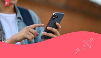 صورة مقربة لسياح ذكر يحمل حقيبة ظهر وهو يتفقد هاتفه المحمول