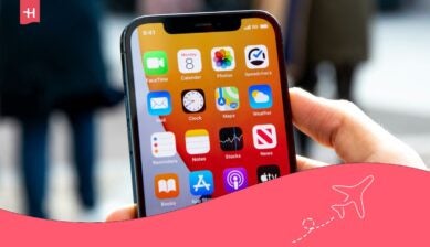 شخص يمسك هاتف آيفون يعرض تطبيقات الشاشة الرئيسية، في صورة توضيحية عن أفضل شريحة بيانات في قطر.