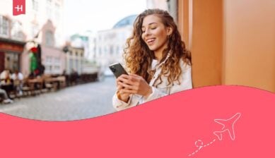 امرأة سعيدة تستخدم هاتفها أثناء سيرها في شارع المدينة.