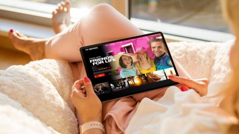 شخص يشاهد مسلسلًا على جهاز لوحي أثناء الاسترخاء في المنزل