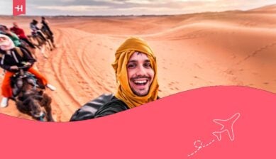 سائح سعيد يستمتع بجولة جماعية على ظهور الجمال في الصحراء