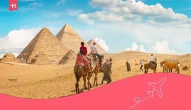 سياح يركبون الجمال أمام أهرامات الجيزة في مصر تحت سماء صافية