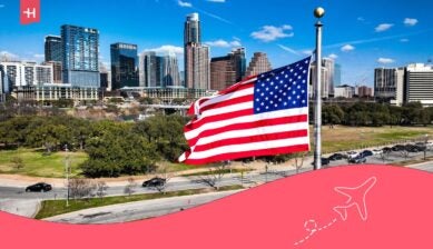 علم الولايات المتحدة الأمريكية يرفرف أمام أفق مدينة حديثة، يرمز لخيارات التجوال الدولي وتوفر خدمات الإنترنت والاتصال للمسافرين إلى أمريكا.