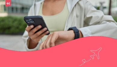 رياضية مجهولة الهوية تحمل هاتفًا محمولًا رقميًا وتتحقق من نتائج جهاز تتبع اللياقة البدنية الخاص بها.