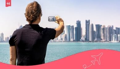 مسافر يلتقط صورة لأفق الدوحة بهاتفه مع الحاجة إلى انترنت في قطر أثناء السفر