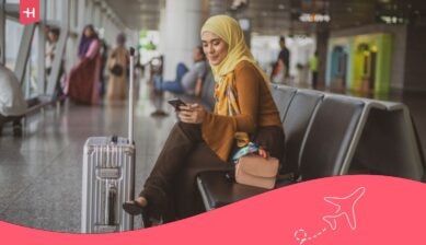 مسافرة تتصفح هاتفها في المطار للاطلاع على باقات التجوال فودافون قبل رحلتها