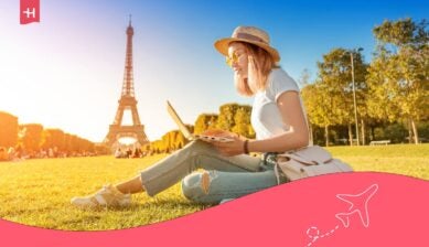امرأة تستخدم جهاز كمبيوتر محمول بالقرب من برج إيفل في باريس أثناء الاستمتاع بالإنترنت في فرنسا.