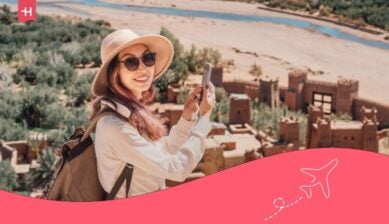 سائحة آسيوية تبتسم وتلتقط صوراً لقرية آيت بن حدو القديمة أو القصر المغربي بهاتفها الذكي