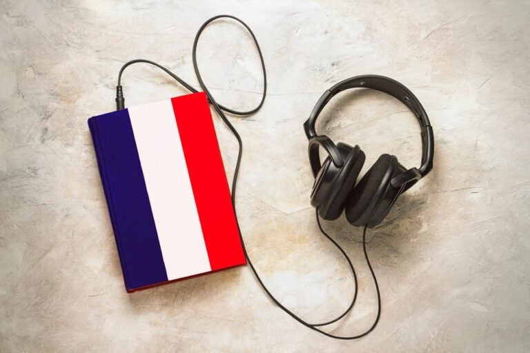 كتاب بألوان العلم الفرنسي بجانب سماعات رأس، في إشارة إلى الاستماع إلى المحتوى الفرنسي.