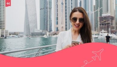امرأة تقف في دبي مارين وتنظر إلى هاتفها.