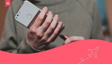 لقطة مقربة ليدَي امرأة توصلان هاتفاً ذكياً أبيض بالشاحن