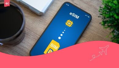 Yurt dışı için en iyi eSIM hakkındaki bir makale için öne çıkan görsel olarak arka planda bir fincan kahve ve ekranda eSIM ile SIM kelimelerinin yazılı olduğu telefon