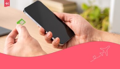 En iyi uluslararası SIM (Seyahat SIM) hakkındaki bir makale için öne çıkan görsel olarak bir elinde telefon, diğer elinde fiziksel bir SIM kart tutan kişi