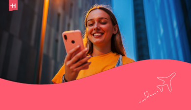 Smilende jente som ser på telefonen sin – utvalgt bilde for en artikkel om Vodafone Travel eSIM.