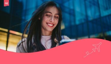 En kvinne som ser på telefonen sin med et stort smil, som hovedbilde til en artikkel om Fjordkraft eSIM