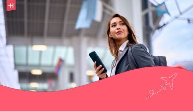 En kvinne på flyplassen med en smarttelefon i hendene, som hovedbilde til en Saily eSIM-anmeldelse