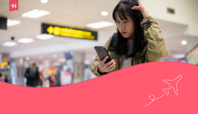 Kvinne som ser på mobilen sin på flyplassen – hovedbilde til en artikkel om Plussmobil eSIM