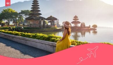 Kvinne i gul kjole ser ut over et tempelområde ved vannet på Bali